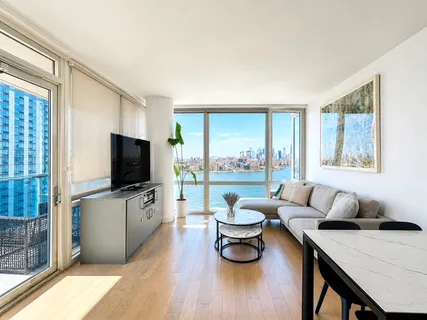 a living room with furniture a flat screen tv and a floor to ceiling window