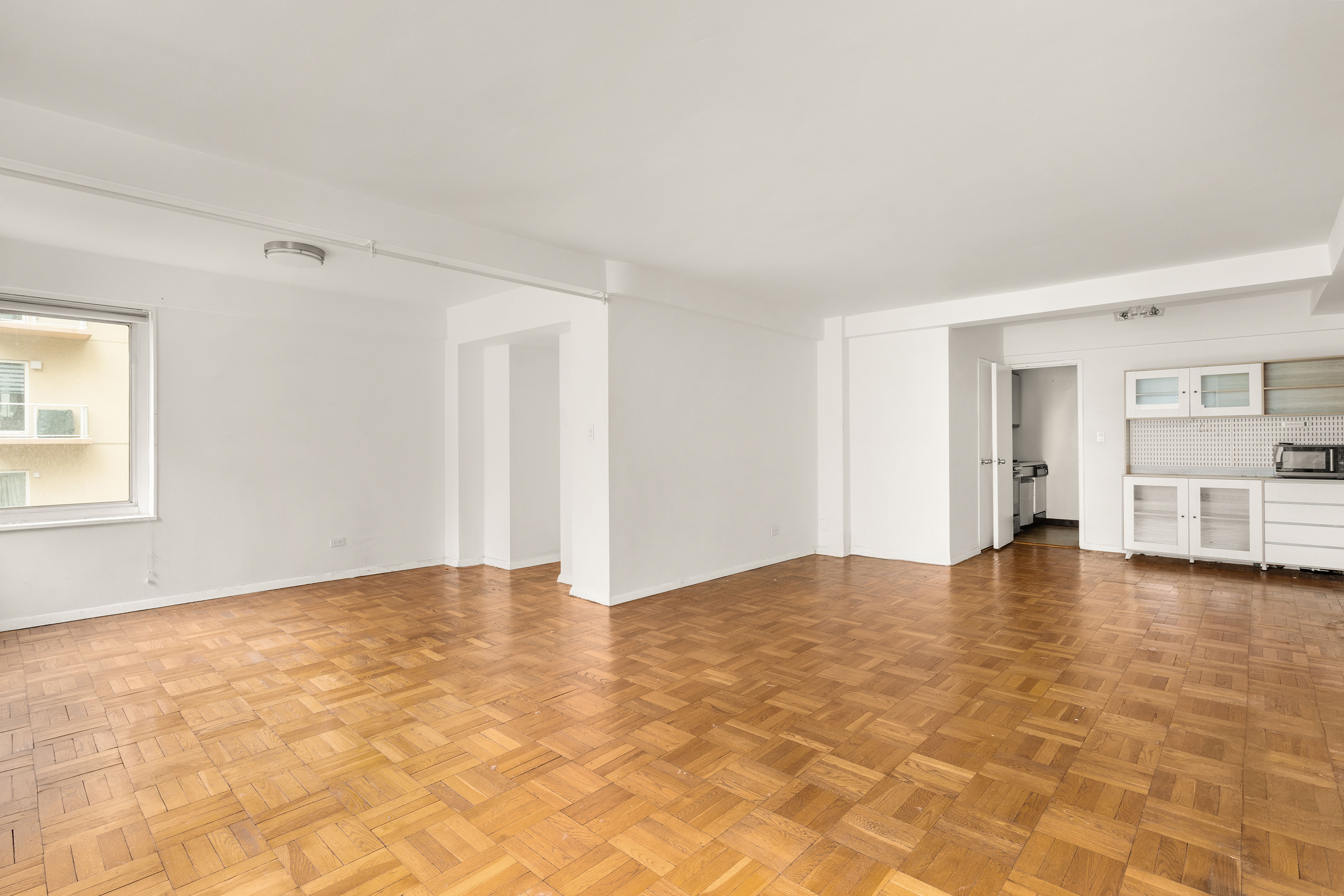 249 East 48th Street, Unit 12A Manhattan, NY 10017 - Photo 8 of 9 a view of empty room with kitchen view and window