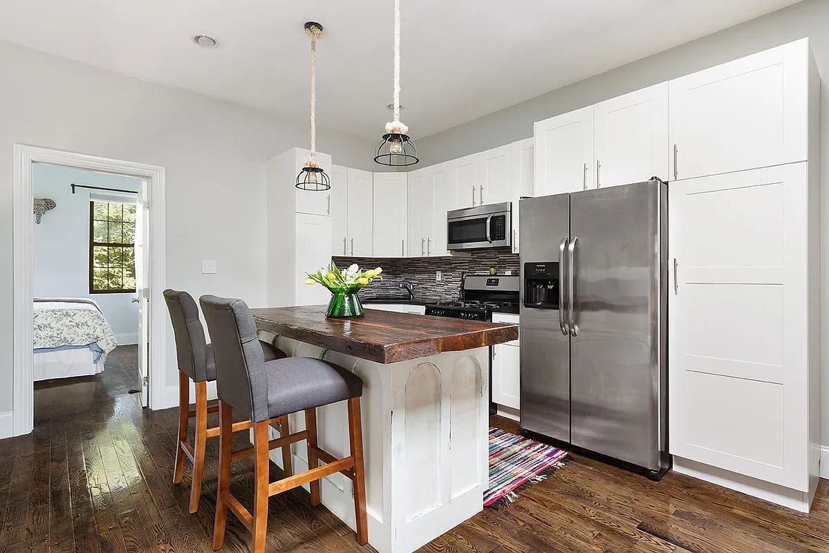 96 Sackman Street Brooklyn, NY 11233 - Photo 4 of 10 a kitchen with stainless steel appliances a refrigerator a stove a dining table and chairs