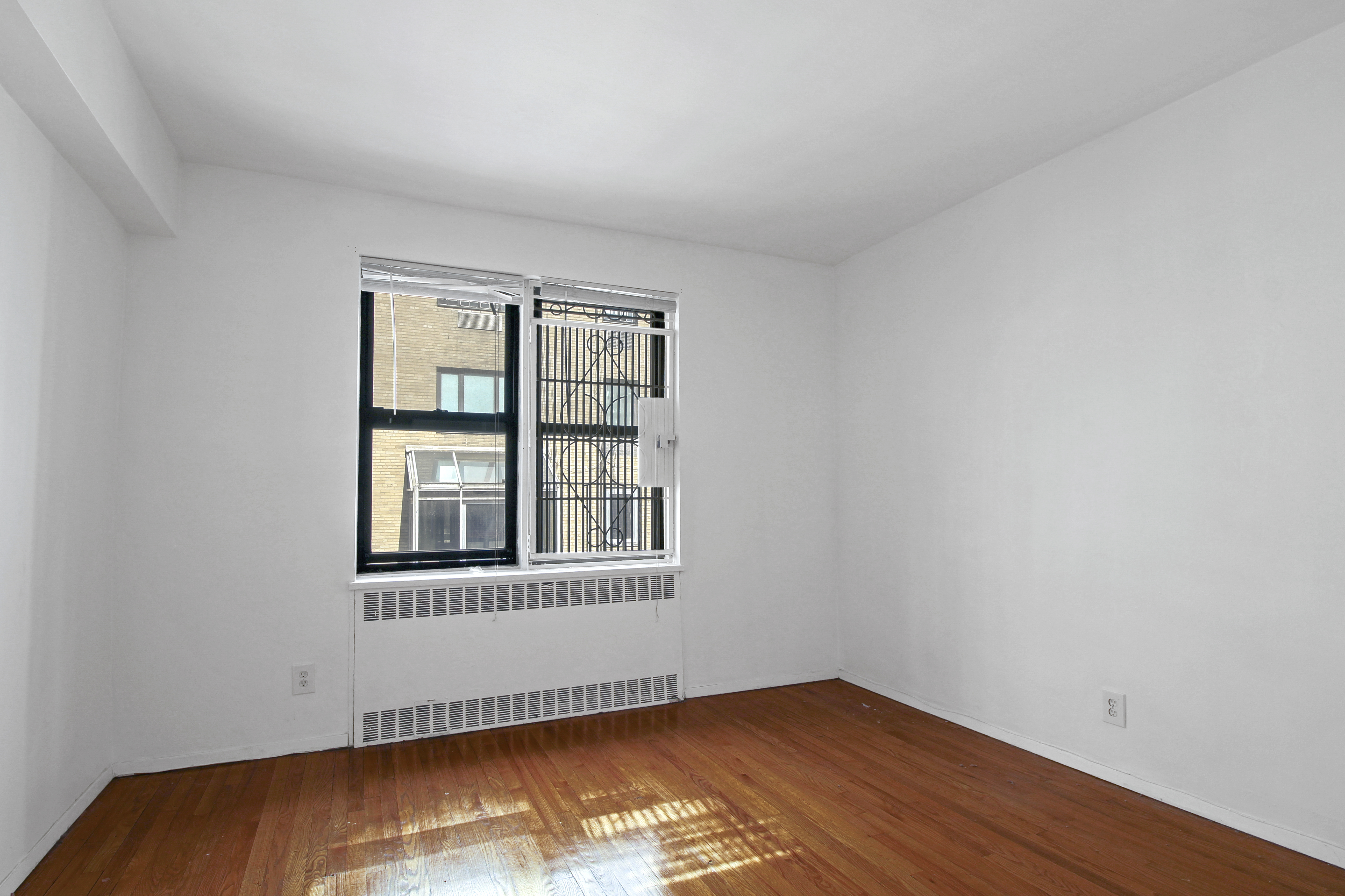 315 East 56th Street, Unit 6C Manhattan, NY 10022 - Photo 4 of 5 a view of an empty room with wooden floor and a window