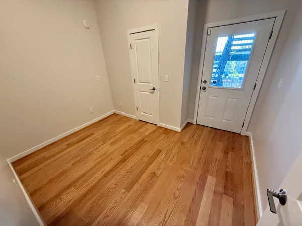 an empty room with wooden floor and windows