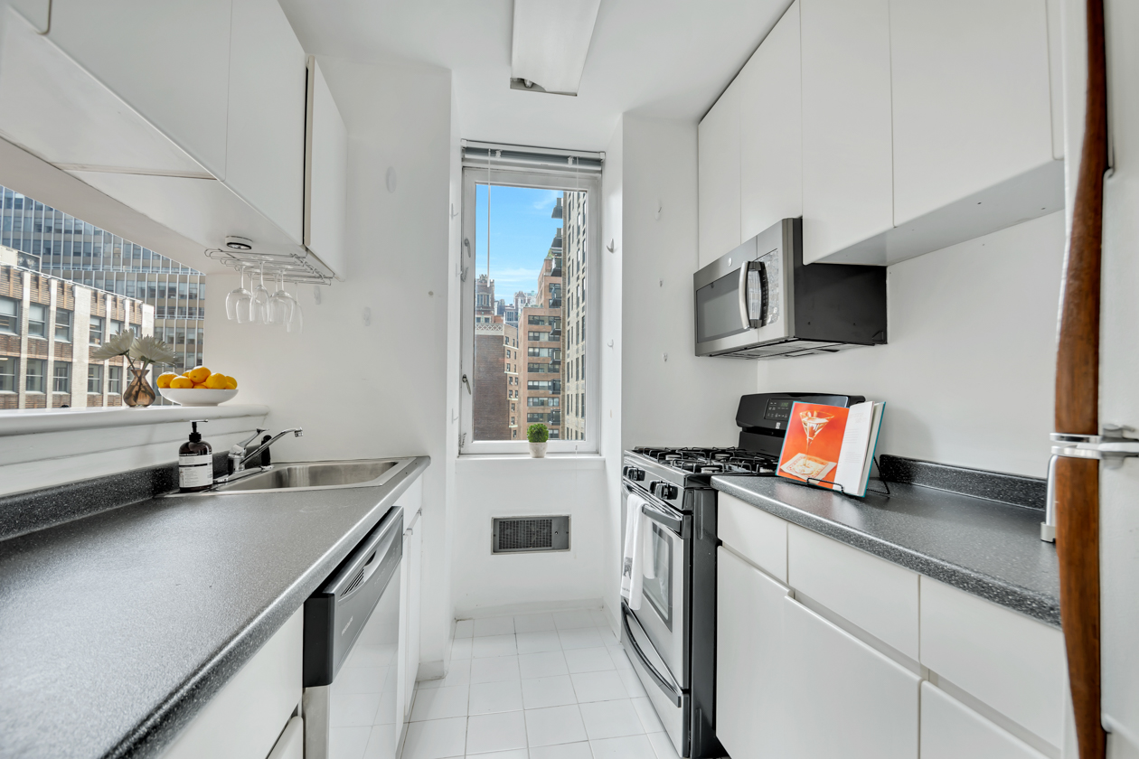 235 East 40th Street, Unit 11G Manhattan, NY 10016 - Photo 4 of 20 a kitchen with stainless steel appliances a sink a stove and a wooden floor