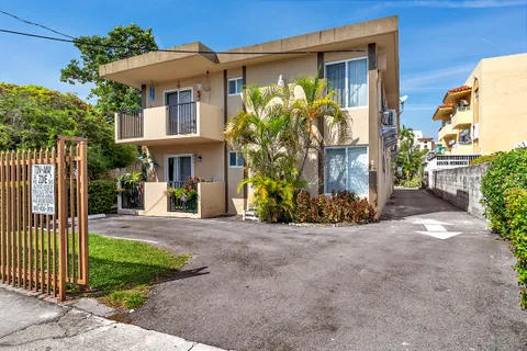 a view of a house with brick walls plants and palm trees