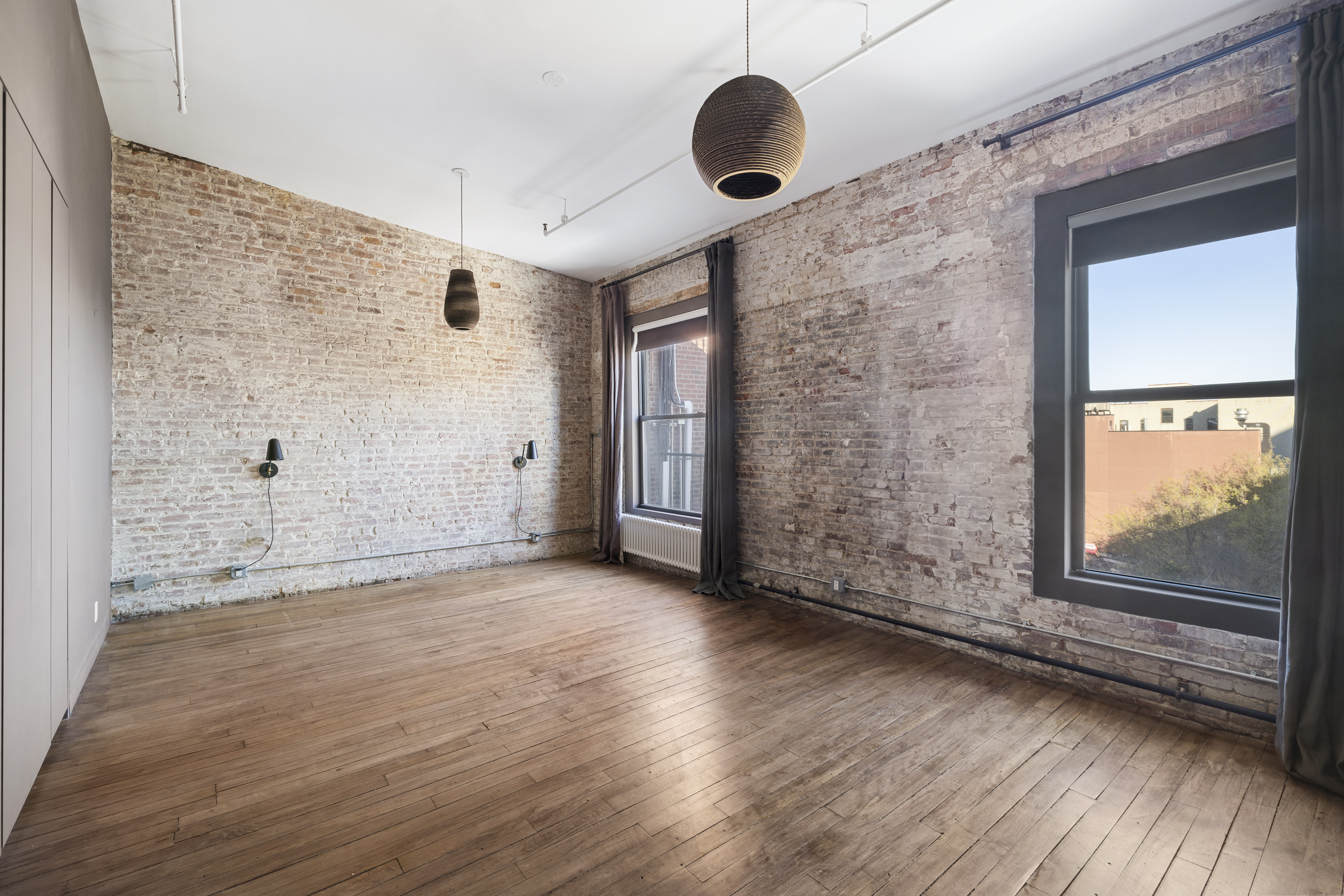 705 Driggs Avenue, Unit 13 Brooklyn, NY 11211 - Photo 8 of 15 an empty room with wooden floor and windows