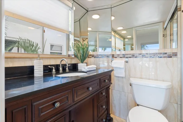 a bathroom with a granite countertop toilet sink and mirror
