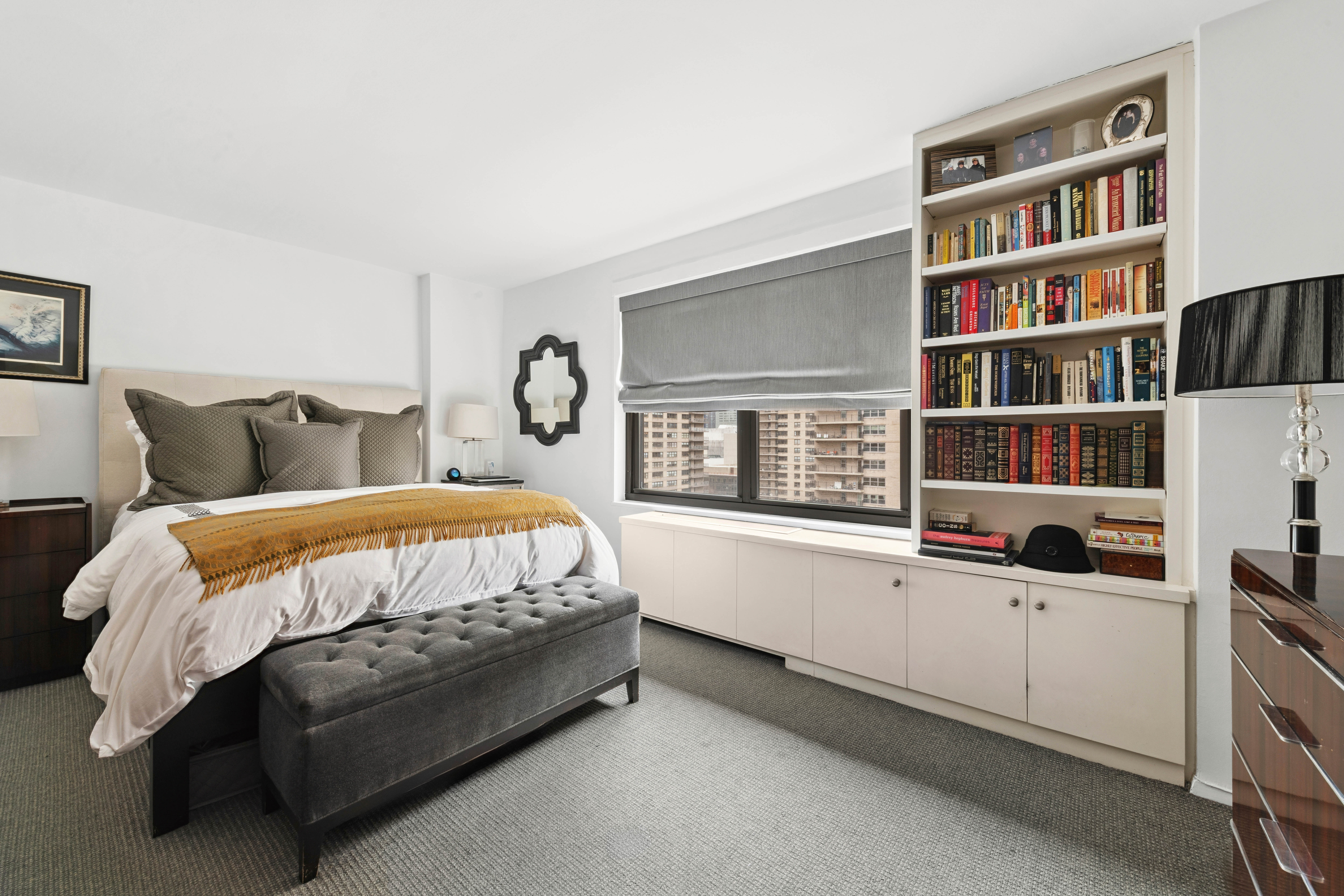 180 West End Avenue, Unit 14G Manhattan, NY 10023 - Photo 4 of 9 a bed sitting in a bedroom next to a bookshelf