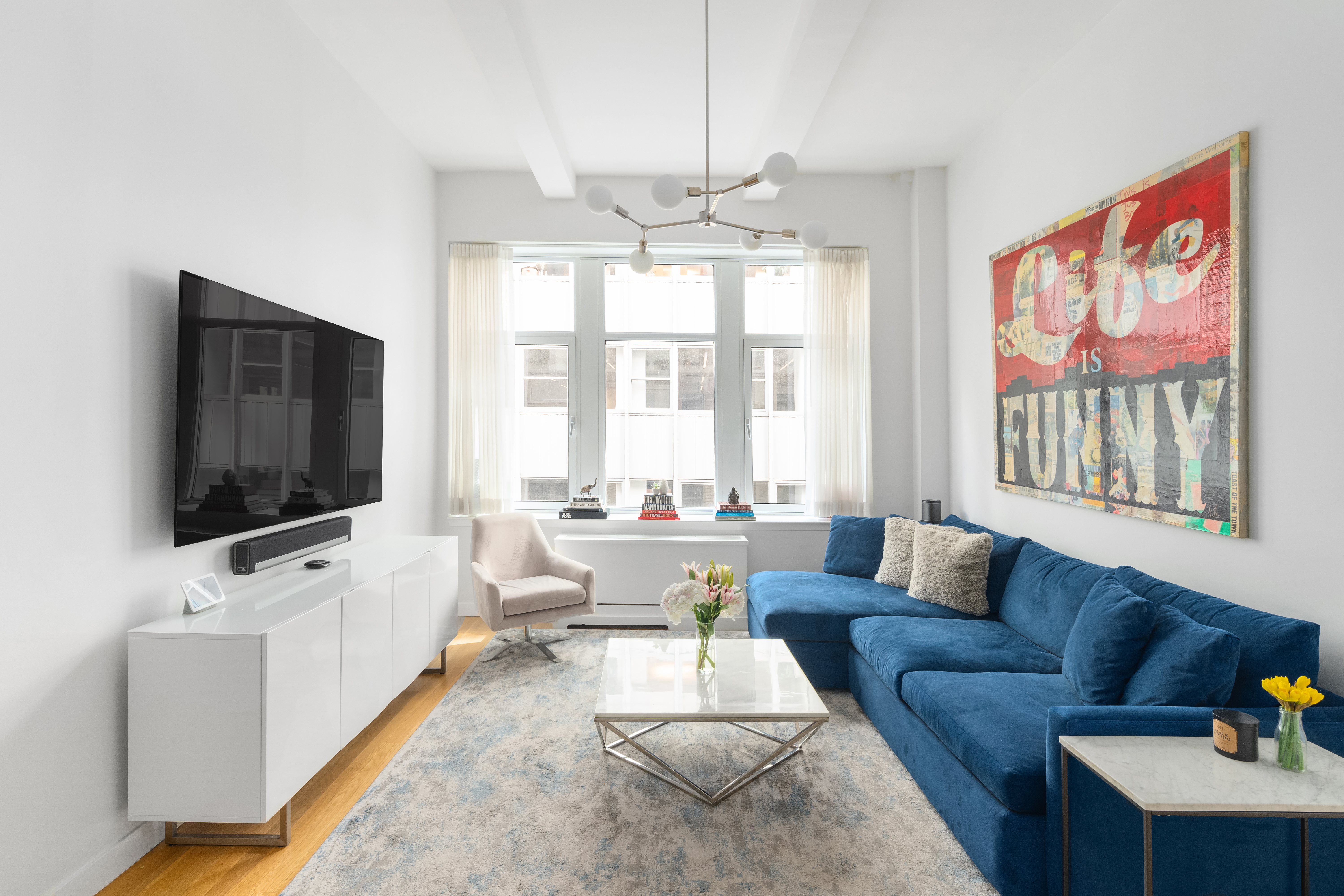 59 John Street, Unit 7D Manhattan, NY 10038 - Photo 1 of 10 a living room with furniture and a flat screen tv
