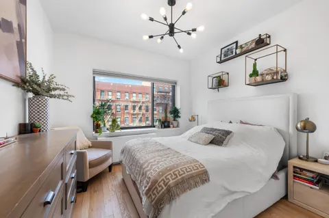 a bedroom with a bed table two chairs and a large window
