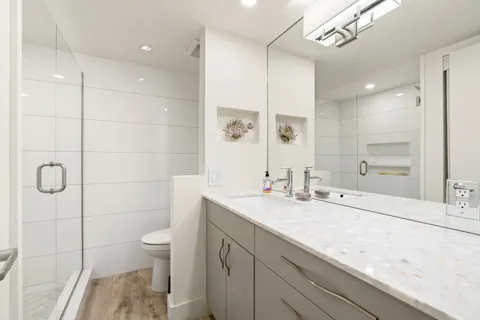 a bathroom with a granite countertop sink a toilet and shower