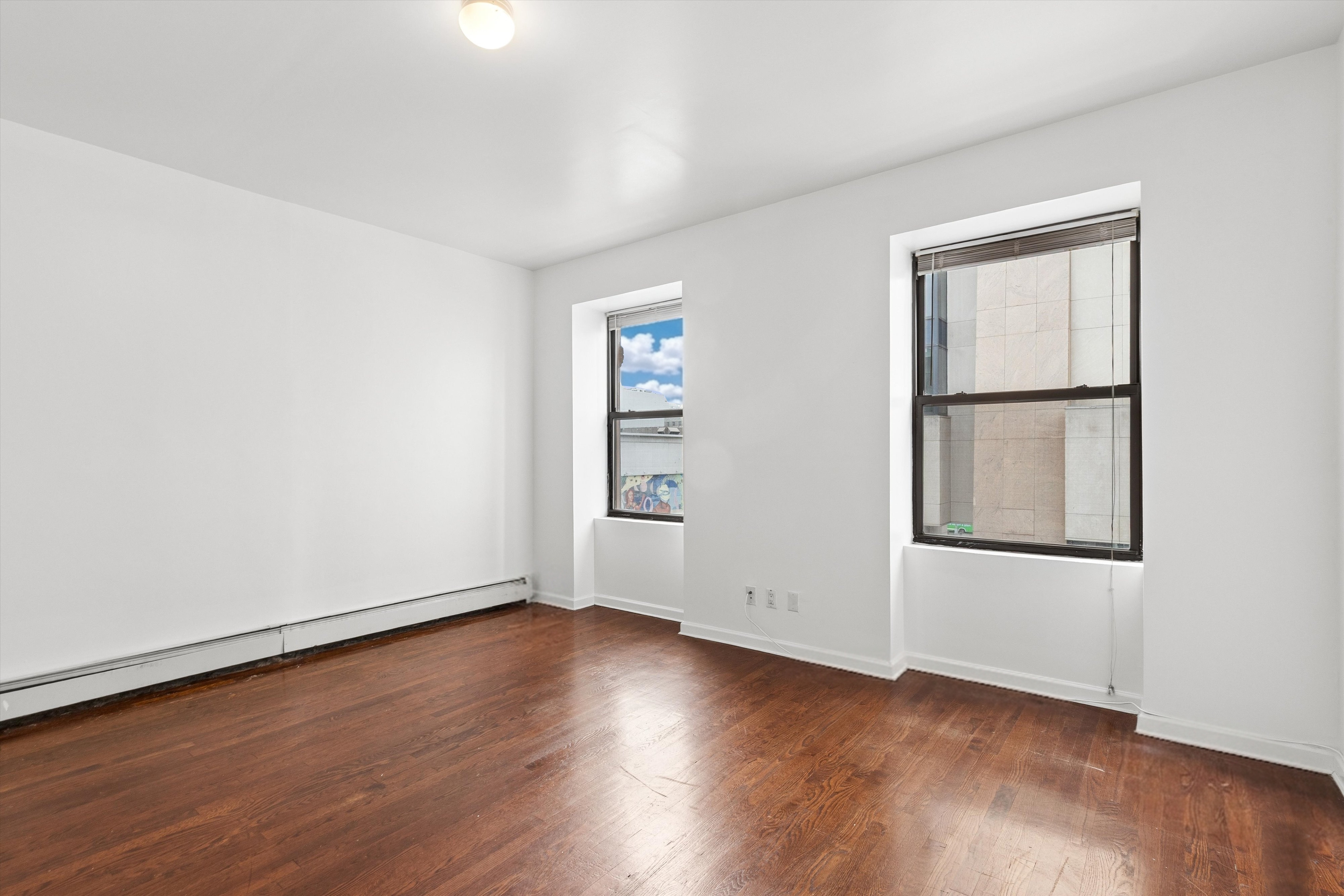 165 West 126th Street Manhattan, NY 10027 - Photo 30 of 40 an empty room with wooden floor and window