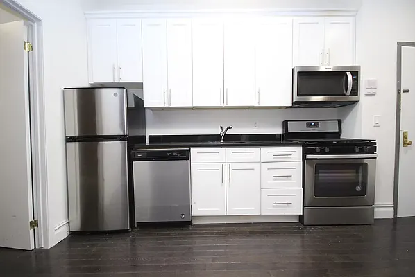 117 Mulberry Street, Unit 2 Manhattan, NY 10013 - Photo 1 of 4 a kitchen with a refrigerator stove and white cabinets