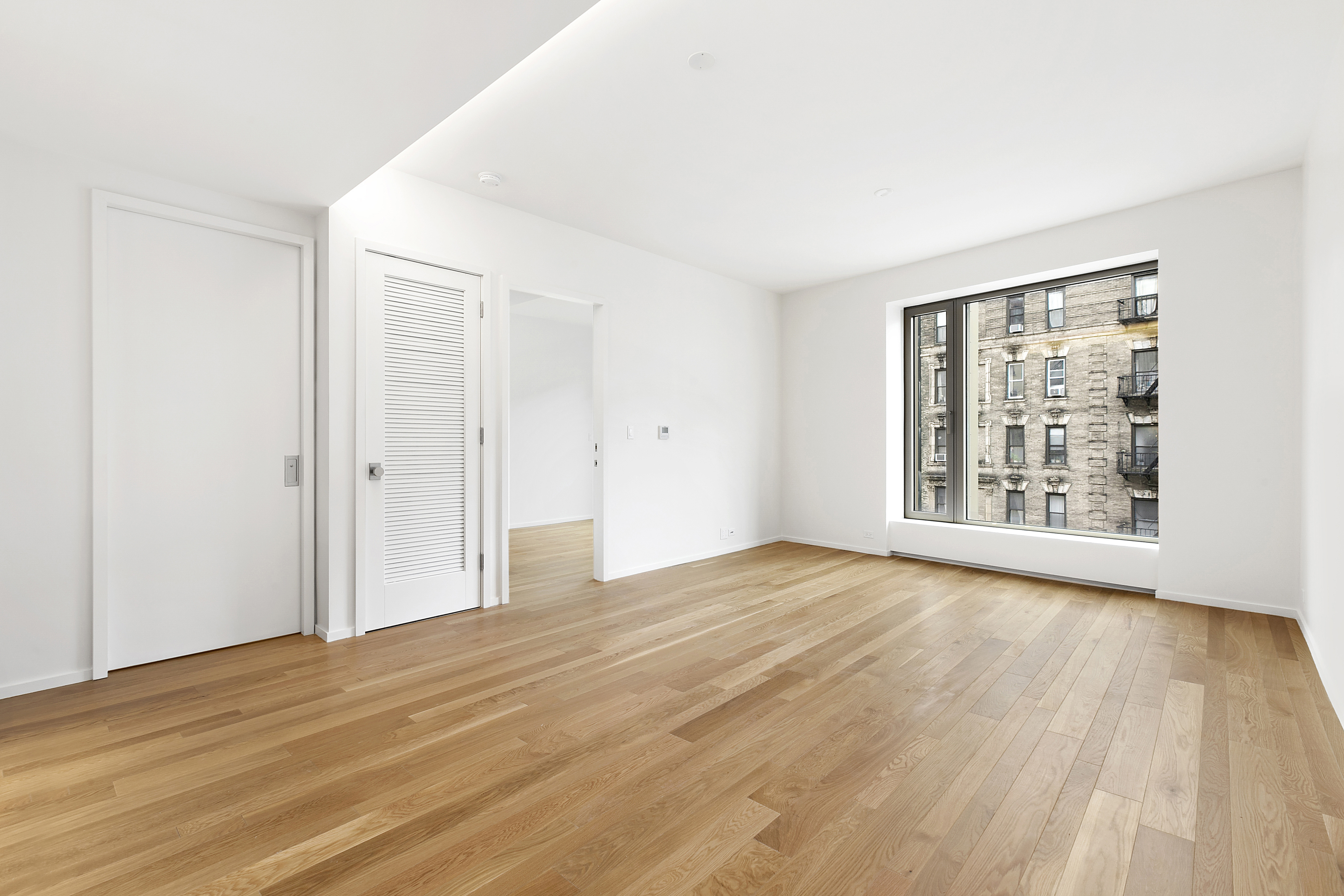 75 Kenmare Street, Unit 3B Manhattan, NY 10012 - Photo 3 of 8 a view of an empty room with wooden floor and a window