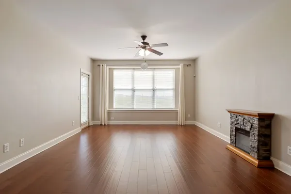 an empty room with wooden floor chandelier and windows