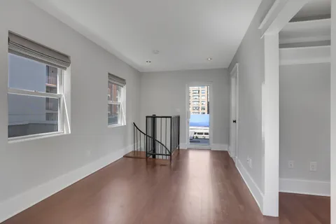 a view of a hallway with wooden floor and a living room