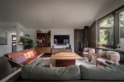 a living room with furniture two window and wooden floor