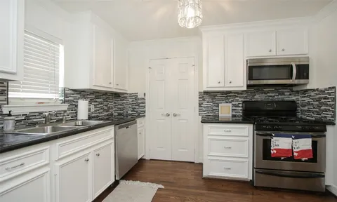 a kitchen with white cabinets and appliances