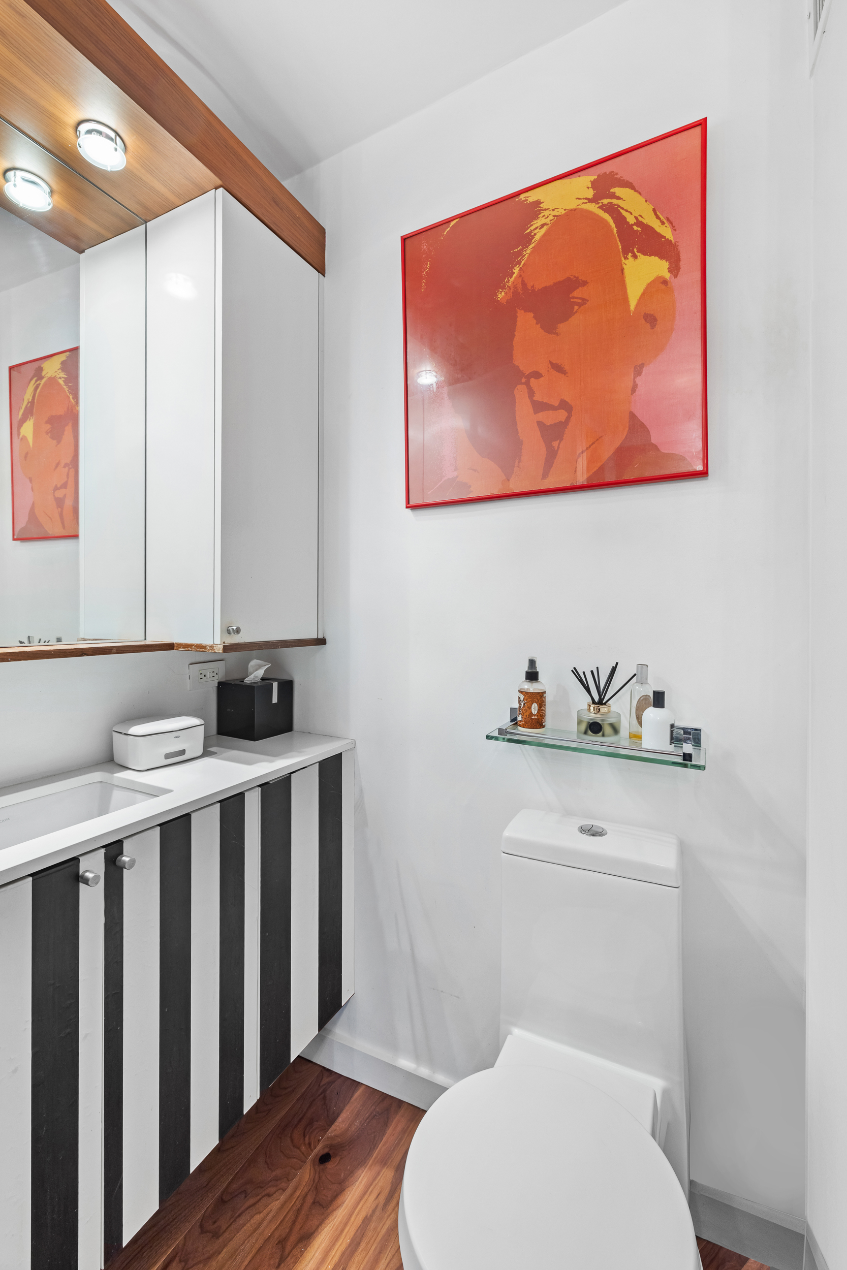 61 West 62nd Street, Unit 16D Manhattan, NY 10023 - Photo 8 of 11 a bathroom with a toilet a sink and wooden floor