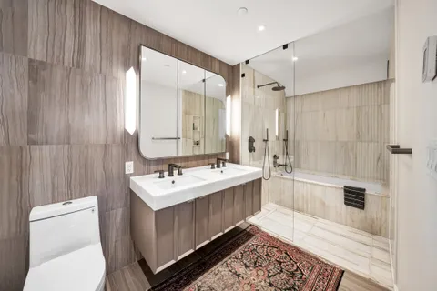 a bathroom with a sink a toilet a mirror and shower