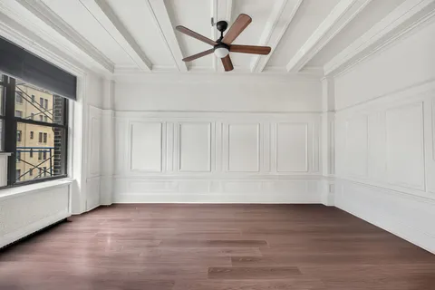 a view of an empty room with a window and wooden floor