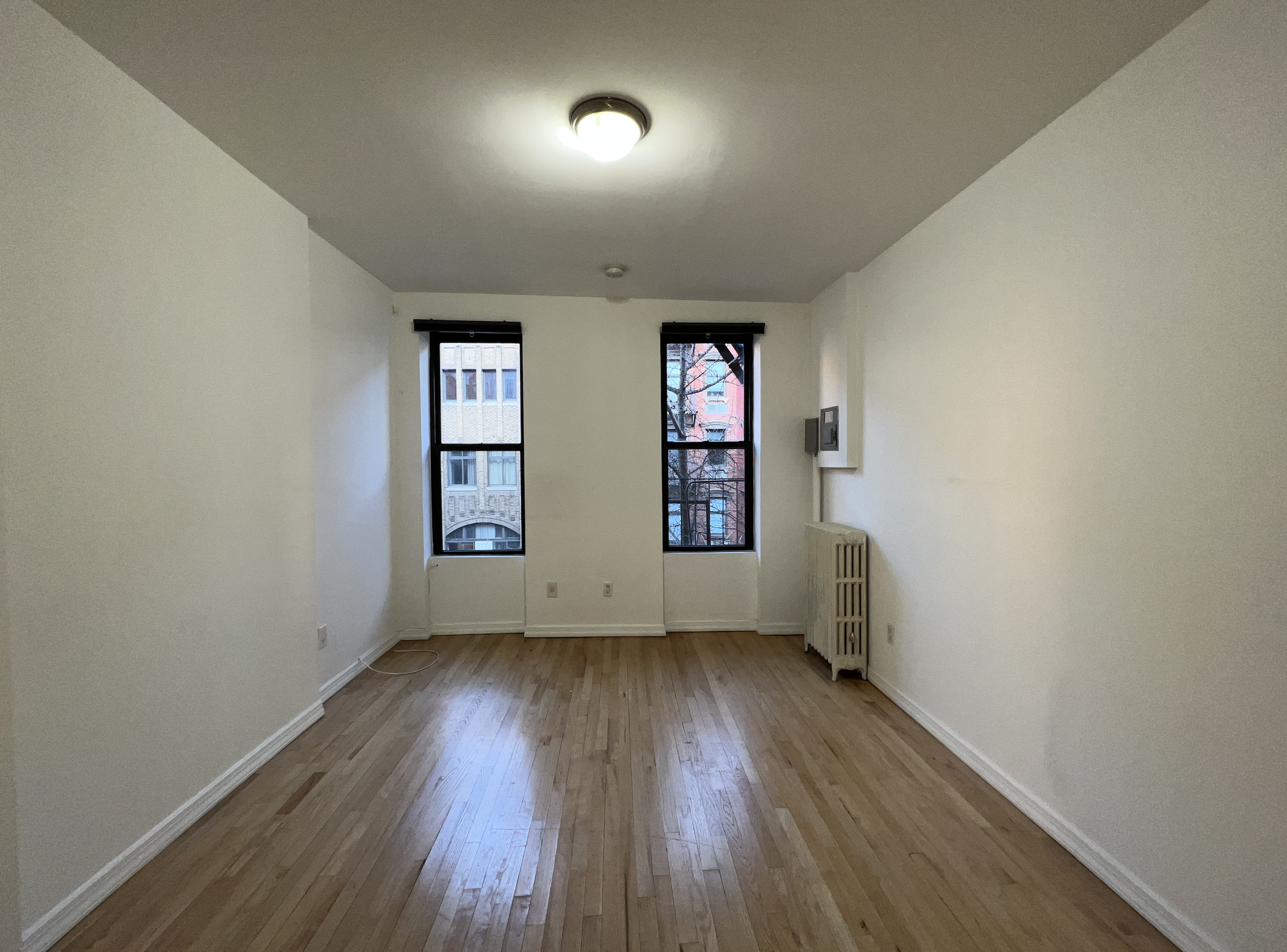 446 West 46th Street, Unit 5 Manhattan, NY 10036 - Photo 3 of 15 wooden floor in an empty room with a window