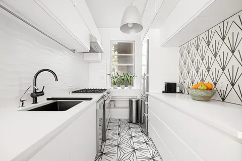 a kitchen with stainless steel appliances a sink a stove and a refrigerator with wooden floor