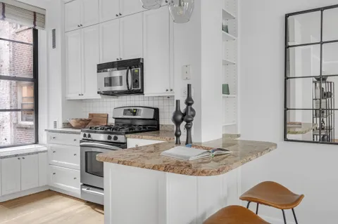 a kitchen with granite countertop a stove a sink and a refrigerator