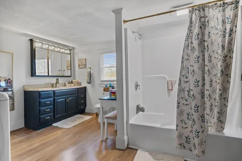 a spacious bathroom with a granite countertop sink a mirror a bathtub and shower