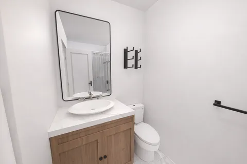 a bathroom with a granite countertop toilet a sink and a mirror