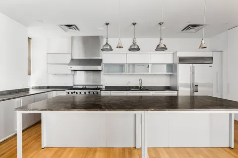 a kitchen with kitchen island granite countertop a sink a stove and white cabinets