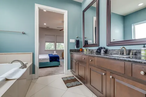 a spacious bathroom with a double vanity sink a mirror and a bathtub