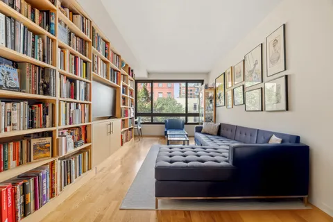 a living room with a couch bookshelf and a large window