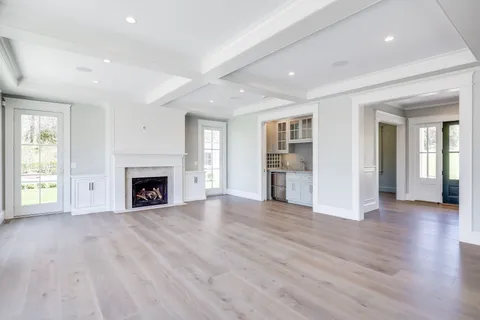 an empty room with wooden floor fireplace and windows