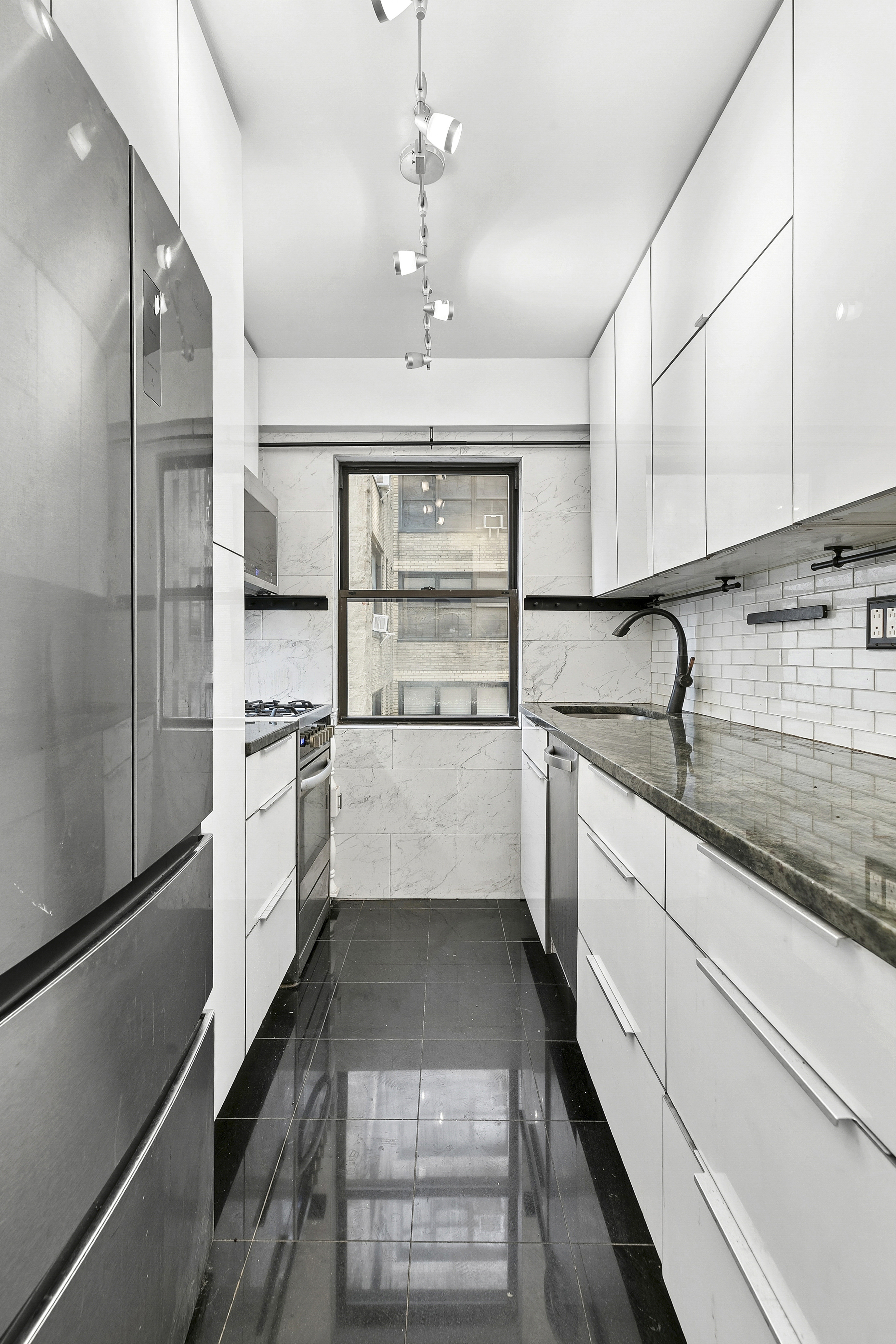 411 East 57th Street, Unit 4B Manhattan, NY 10022 - Photo 4 of 7 a kitchen with white cabinets and white appliances