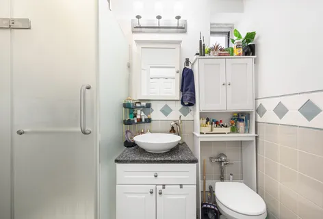 a bathroom with a granite countertop sink and a toilet