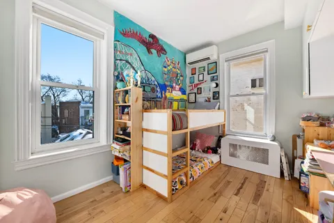 a view of a bedroom with baby crib and wooden floor