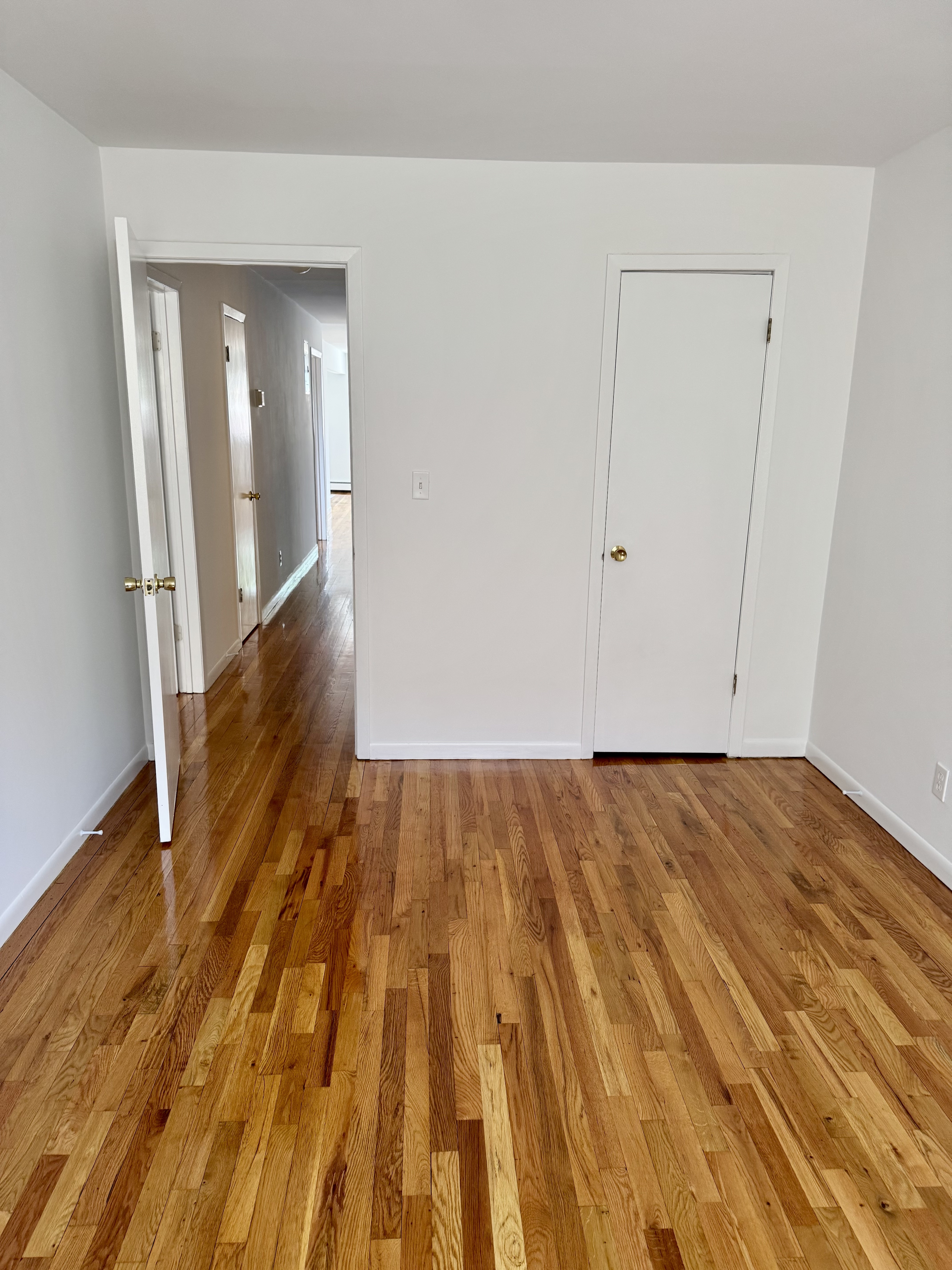 59-15 39th Avenue, Unit 2 Queens, NY 11377 - Photo 12 of 13 wooden floor in a hall with an empty room