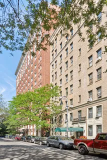 a front view of a building with lot of cars and trees