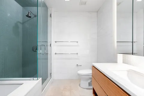 a bathroom with a granite countertop sink toilet and shower