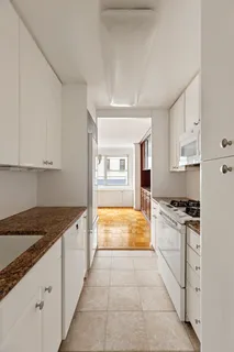 a kitchen with granite countertop a stove and white cabinets