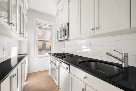 a kitchen with granite countertop a sink stove and cabinets