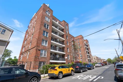 a front view of a building with lot of cars and trees
