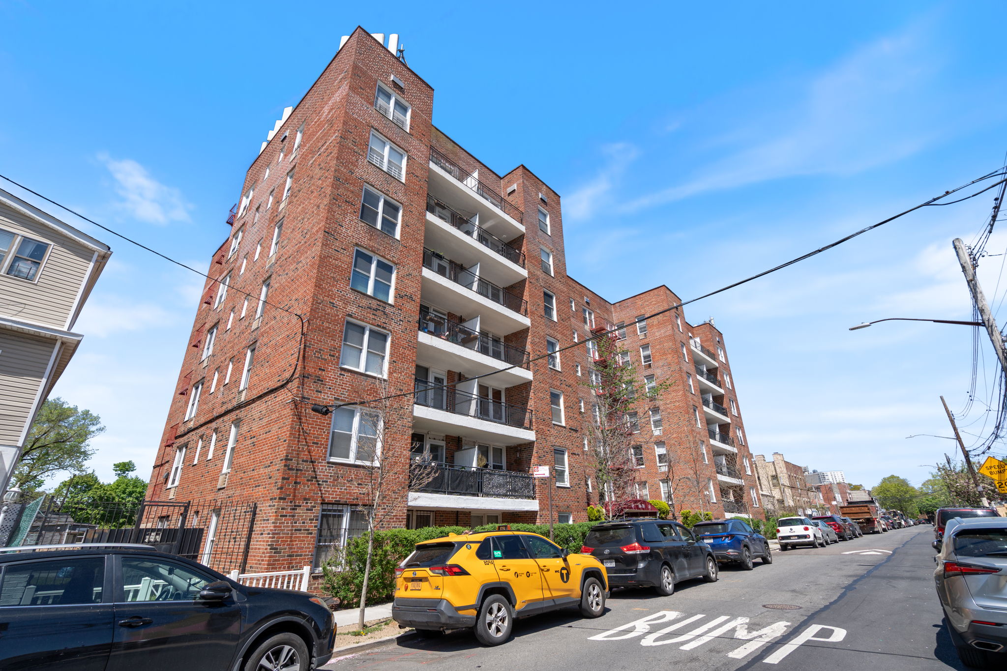 a front view of a building with lot of cars and trees