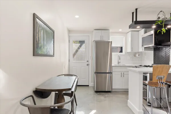 a kitchen with stainless steel appliances refrigerator stove microwave and chair