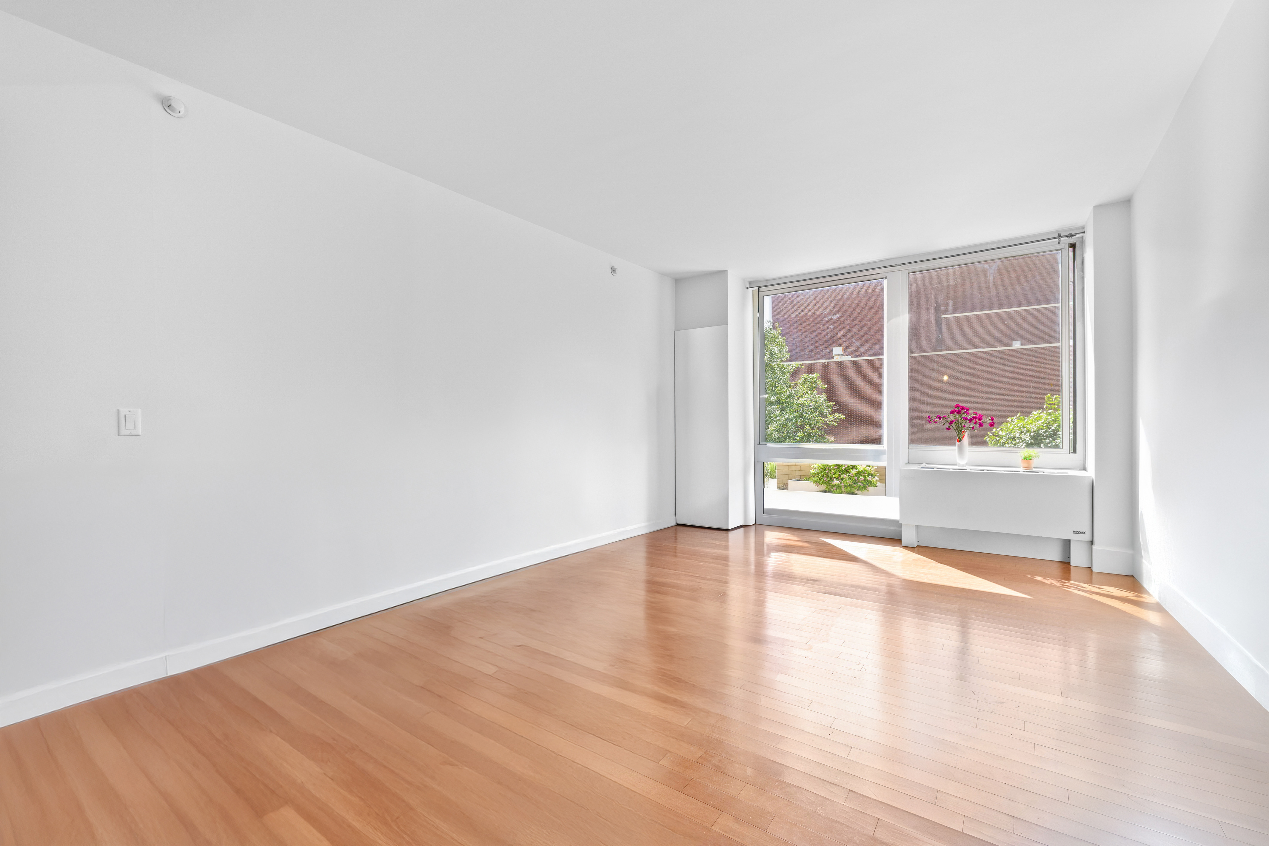 107-24 71st Road, Unit 2E Queens, NY 11375 - Photo 2 of 18 a view of an empty room with wooden floor and a window