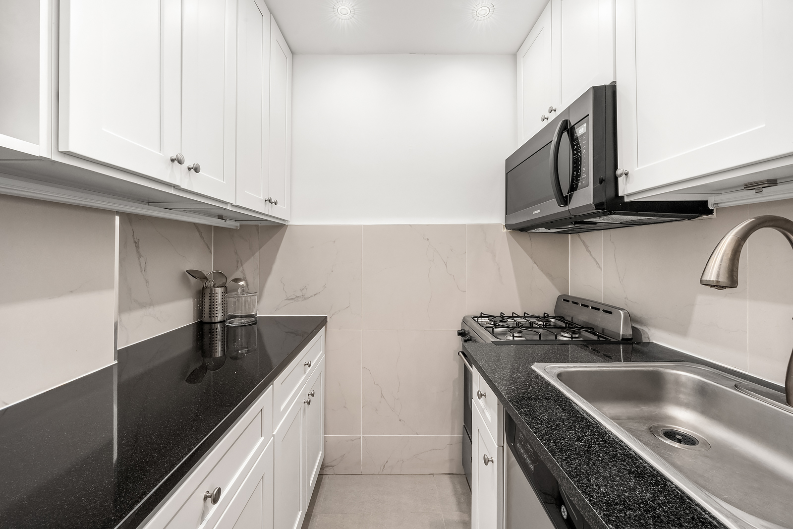 215 East 77th Street, Unit 4C Manhattan, NY 10075 - Photo 2 of 7 a kitchen with stainless steel appliances granite countertop a sink stove and microwave