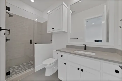 a bathroom with a granite countertop sink a toilet and a shower