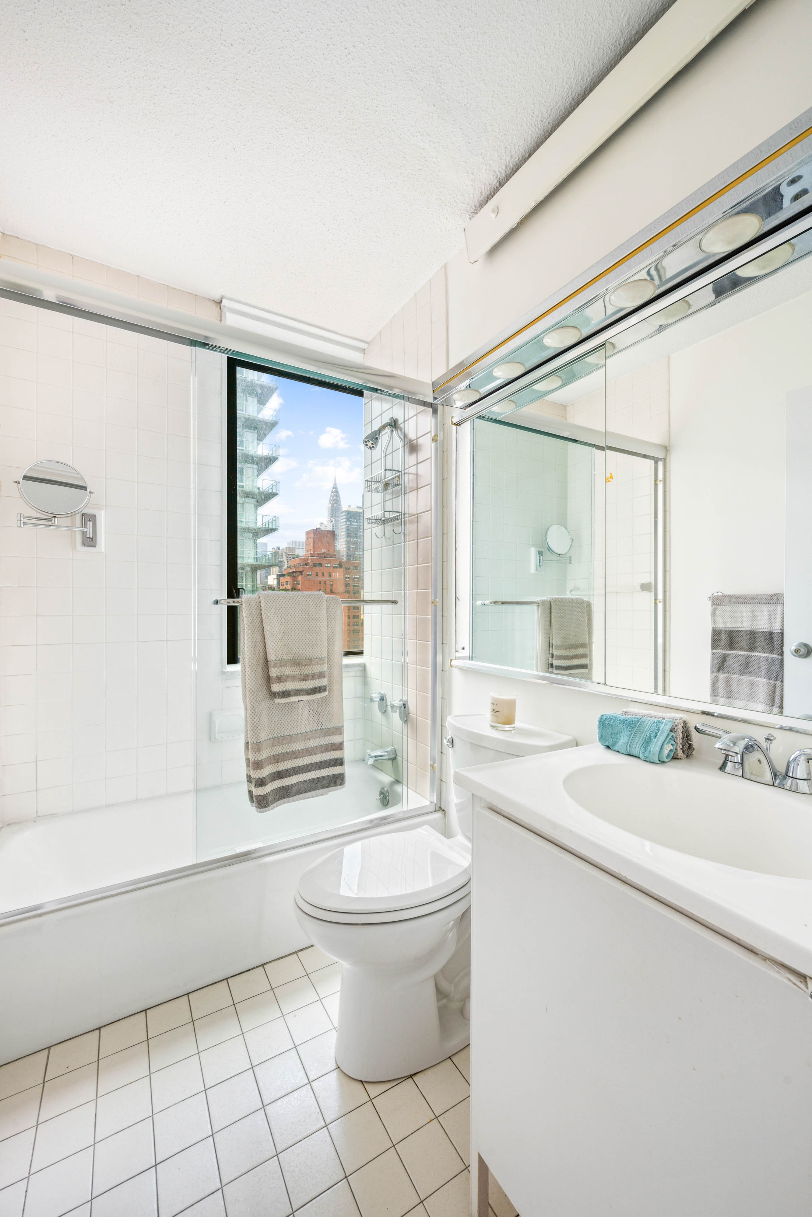 300 East 54th Street, Unit 15C Manhattan, NY 10022 - Photo 5 of 10 a bathroom with a sink a toilet a mirror and a shower