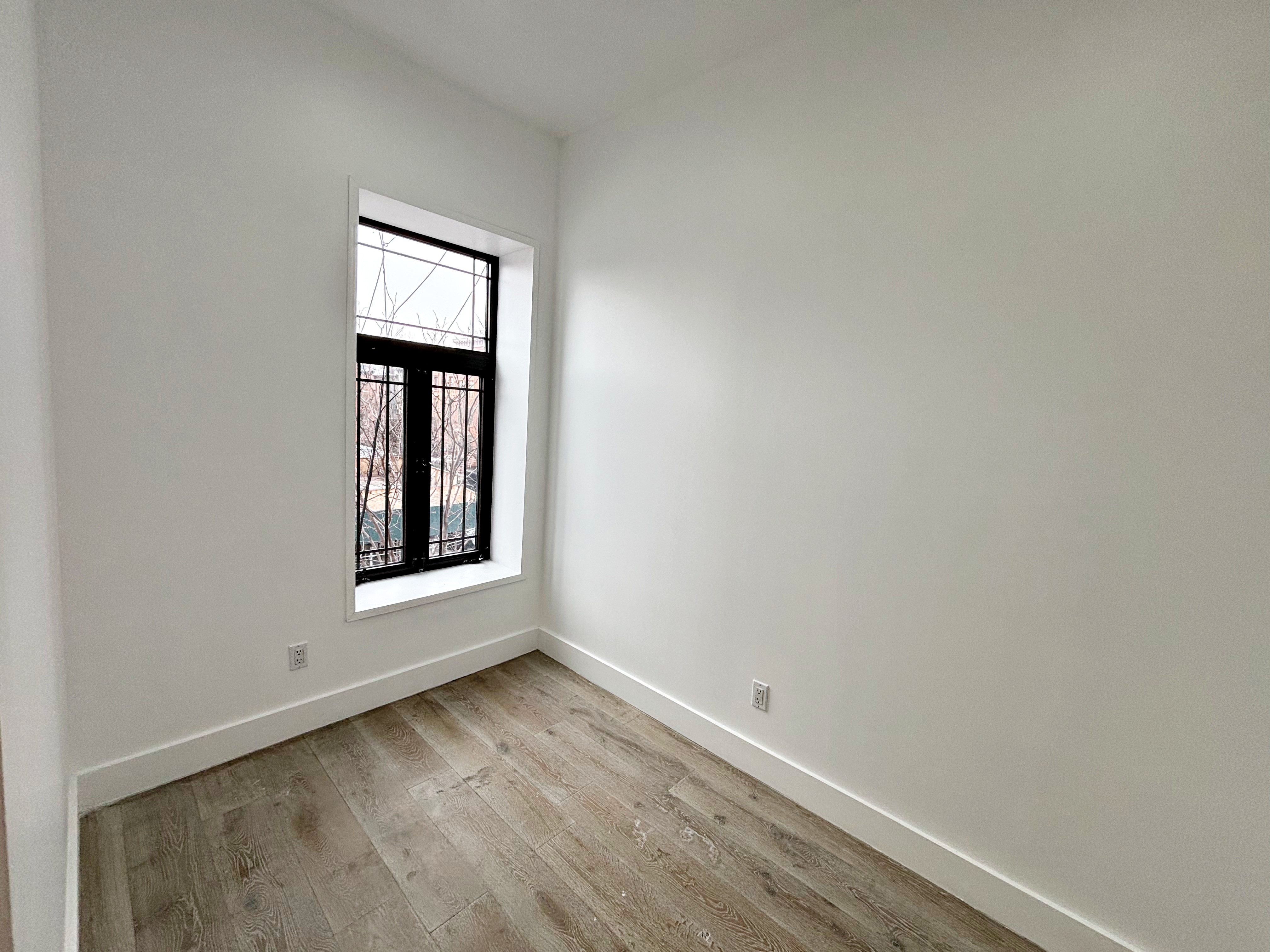 385 Nostrand Avenue, Unit Undisclosed Brooklyn, NY 11216 - Photo 19 of 27 a view of an empty room with wooden floor and a window