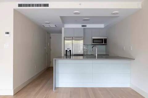 a living room with stainless steel appliances kitchen island granite countertop a rug a stove and a wooden floors