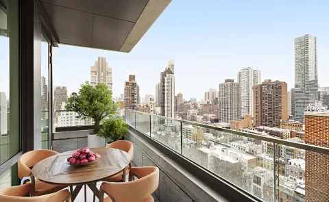 a view of a city from a balcony with dining table and chairs